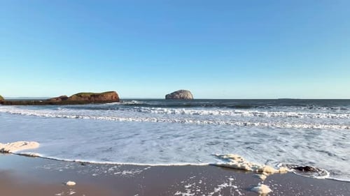 Aerial view of rugged cliff and beach by ocean, Scotland.