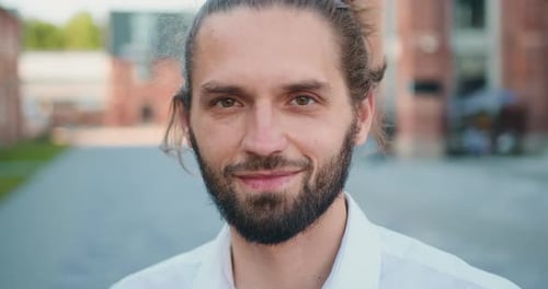 Portrait male face of a happy handsome young man in a urban street. Close up of portrait man looking