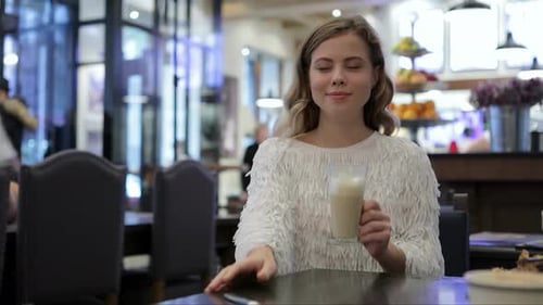 Woman Enjoying a Refreshing Coffee in a Cozy Bakery
