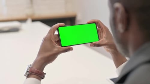 African Man Holding Horizontal Smartphone with Green Screen
