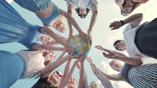 Freunde im Kreis halten einen Globus in der Hand und feiern gemeinsam ihren Abschluss