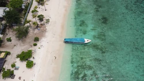 Boats Docked On The Shore Of A White Sand Beach Lined With Palm Trees In Bali, Indonesia. aerial til