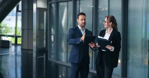 Business colleagues discussing project with tablet in modern office hallway