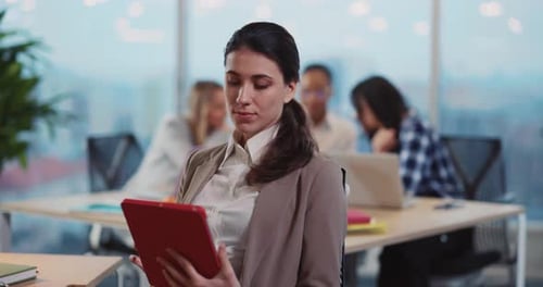 Woman Holding Tablet in Office with Coworkers