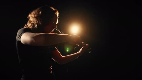 Woman Plays Violin in Dark, Moody Lighting