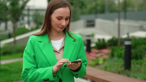 Portrait of a Woman Walking Down the Street of a Modern City An Attractive Woman Using a Smartphone