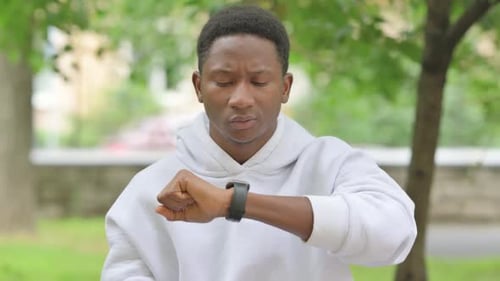 Man Checking Smartwatch in Urban Park Setting