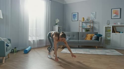 Une belle fille athlétique en forme dans des vêtements d'entraînement fait des exercices Jack Burpee dans son spa lumineux