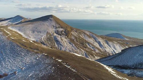 Snowy Mountain Range Meeting Azure Ocean Under Cloudy Sky