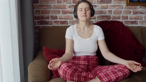 Woman Meditating with Headphones on Couch Indoors