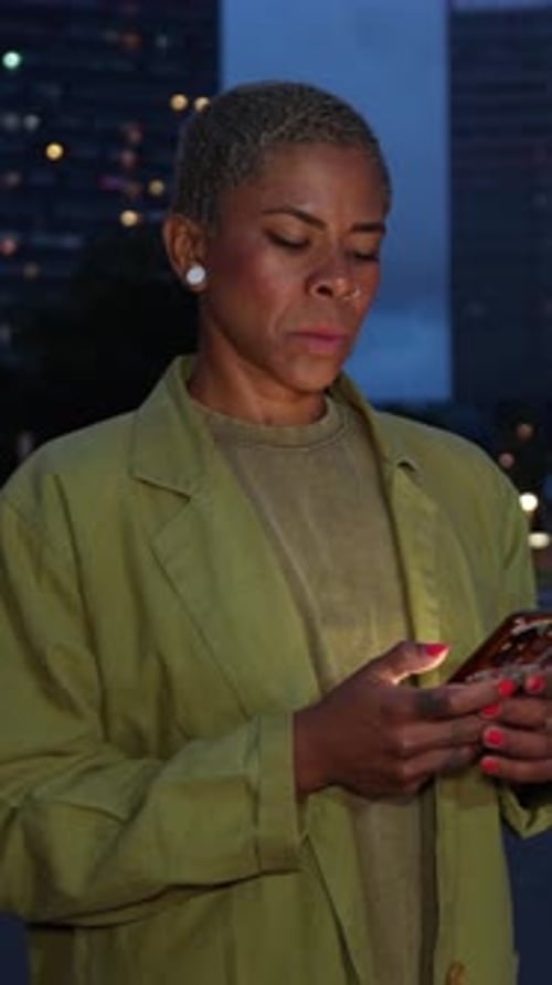 African American Woman Using Smartphone at Night in the City