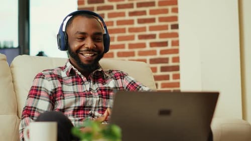 Man Smiling, Relaxing with Laptop and Headphones Inside