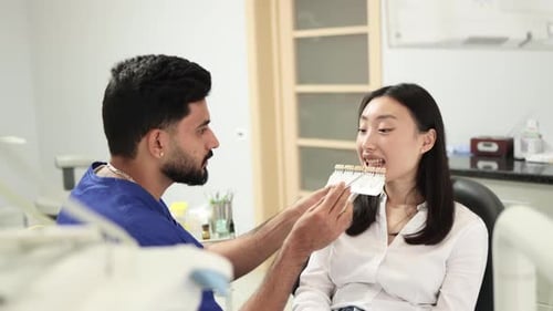 Dentist Examines Young Woman's Teeth Using Shade Guide