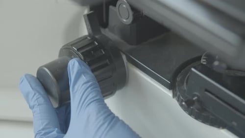 Gloved Hand Adjusts Medical Equipment in Laboratory