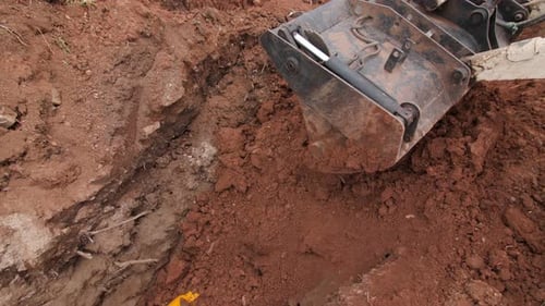 Digger Buries Trench with Pipe Covered with Casing in Ground