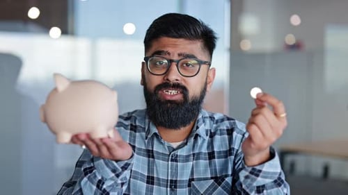 Bearded Businessman Saving Money in Piggy Bank at the Office