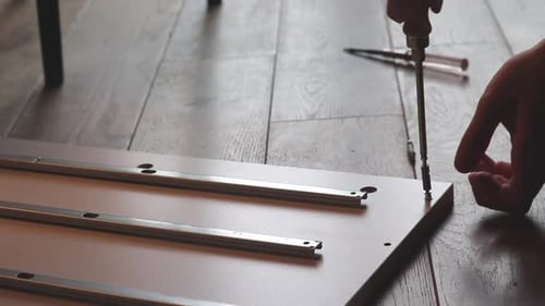 Close Up Of Boy Hand Building A Shelf, Screws In Screw On The Floor
