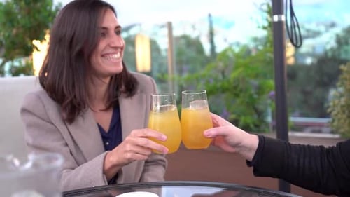 Two Women Toasting Juice on an Urban Terrace