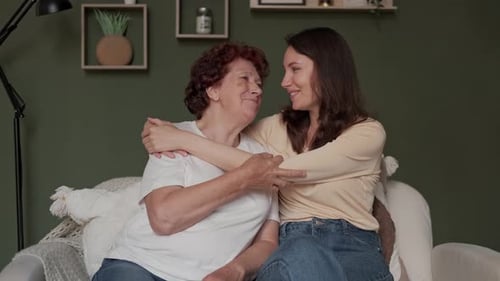 Loving Senior Woman and Young Adult Embracing Indoors