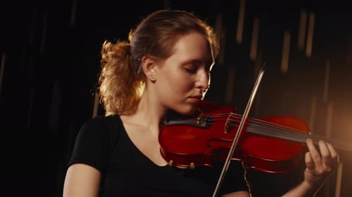 Woman Plays Red Violin with Dramatic Lighting