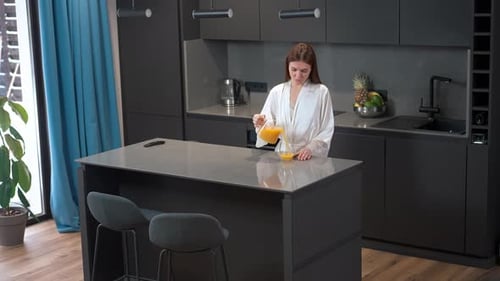 Young Woman Pours Orange Juice at Home