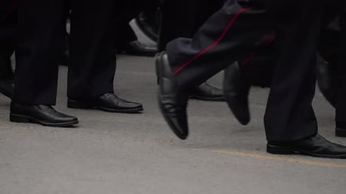 Closeup View of Synchronized Marching Feet Wearing Dark Uniforms with Redstriped Trousers and