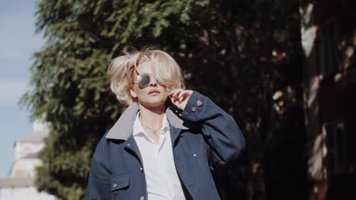 A Beautiful Blonde Girl in a Blue Coat is Walking Autumn Fashion