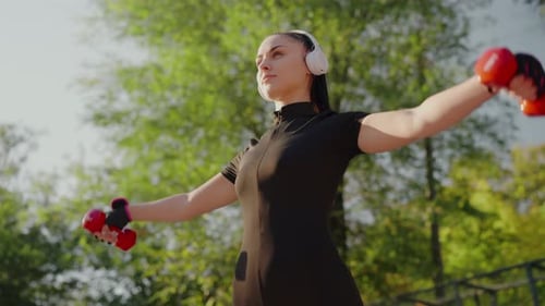 Young Woman Exercises With Dumbbells Outdoors
