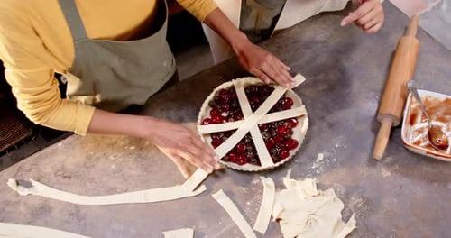 Women Making Cherry Pie Together in a Kitchen