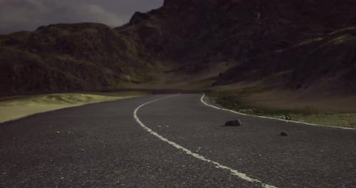 Serene Winding Road Through Rugged Mountains Under a Cloudy Sky