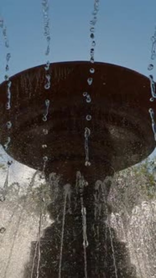 Fountain splashes the water on blue sky with sunrays background