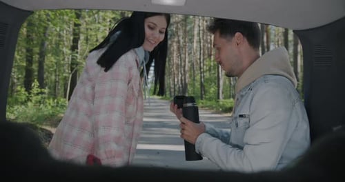 Slow Motion of Young Couple Tourists Drinking Tea From Thermos Sitting in Car Enjoying Vacation