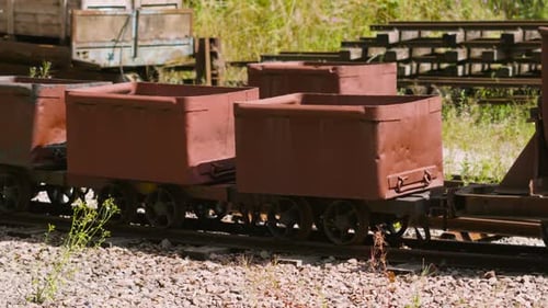 Rusty Mining Carts on Railroad Tracks in Rural Setting