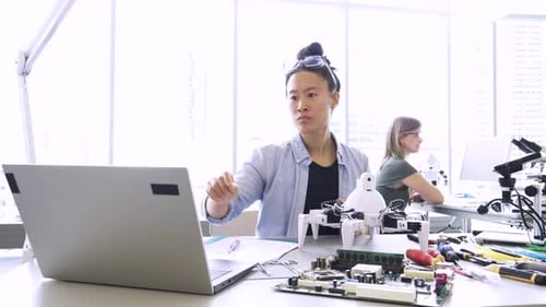 Ingeniera ensamblando robótica en una computadora portátil en un laboratorio para adultos