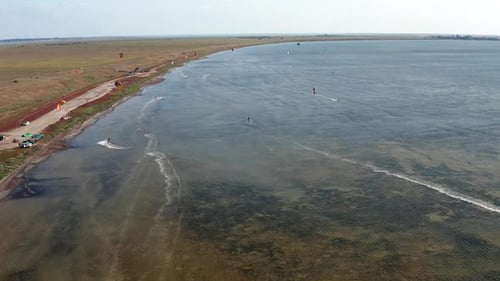 People go kitesurfing on the sea. The wind carries the athlete along the sea waves.