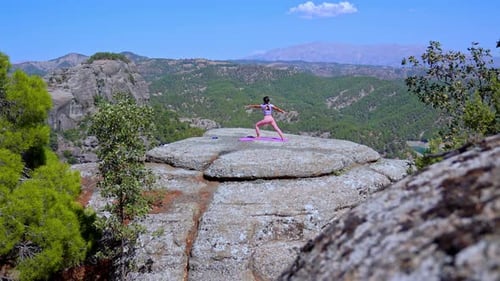 Wide Shot of Woman Practicing Yoga on Cliff with Mountain Landscape