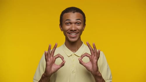 Smiling Man Gives Okay Sign on Yellow Background