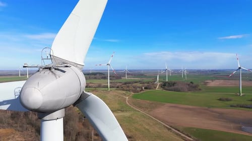 drone footage of wind turbines in a wind farm generating green electric energy on a wide green field
