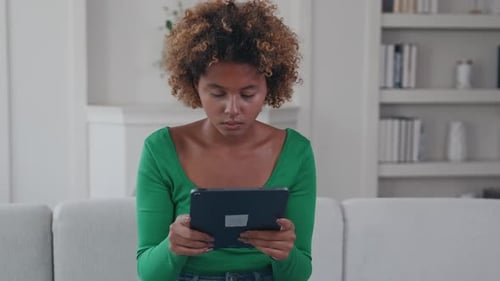 Woman Using Tablet Device While Sitting on Couch