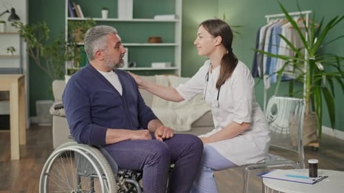 Supportive Doctor Comforting Man in Wheelchair