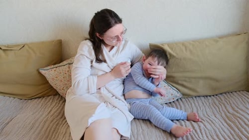 Mother Wipes Toddler's Nose on Bed