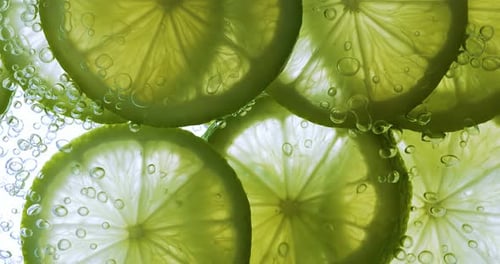 Limettenscheiben, die tief unter Wasser fallen. Aufgenommen mit einer Superzeitlupenkamera mit 1000 Bildern pro Sekunde.