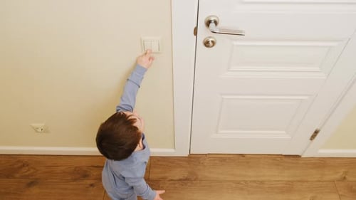 Child Turning on Light Switch Indoors from Above