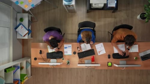 Visão superior do call center ou do departamento de vendas dos trabalhadores trabalhando nas mesas dos computadores usando fones de ouvido