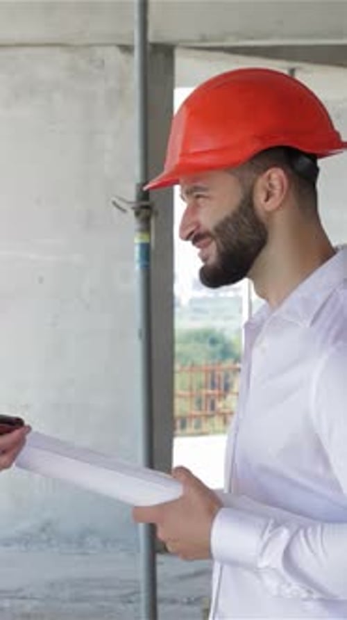 Two Builders Engaged in a Lively Discussion Over a Digital Tablet at a Construction Site
