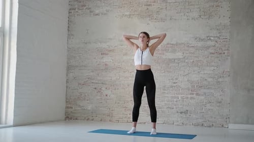 Woman Stretches Neck Muscles Indoors on Mat