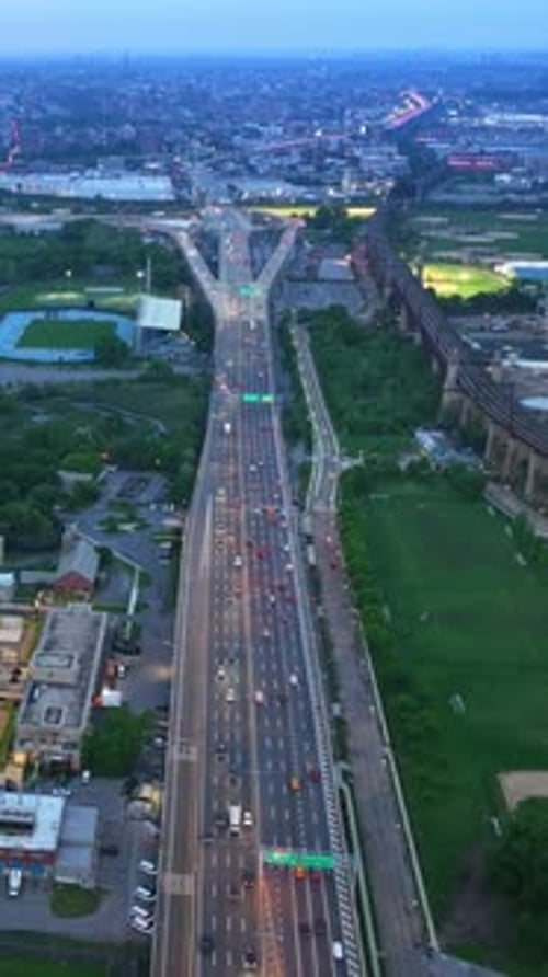 Speed motorway with lots of transport passing by. Drone footage over the city with green parks