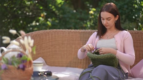 Young Woman Crocheting a Green Handbag Outdoors