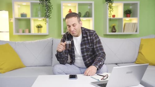 Adult Man Drinking Beverage While Working at Home