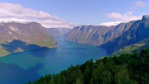 Shadow of clouds moving over the blue Aurlandsfjord in Norway on a sunny day. Backwards drone dolley